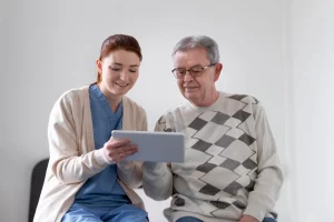 A man and woman sit on a bed, both focused on a tablet in their hands, sharing a moment of engagement.