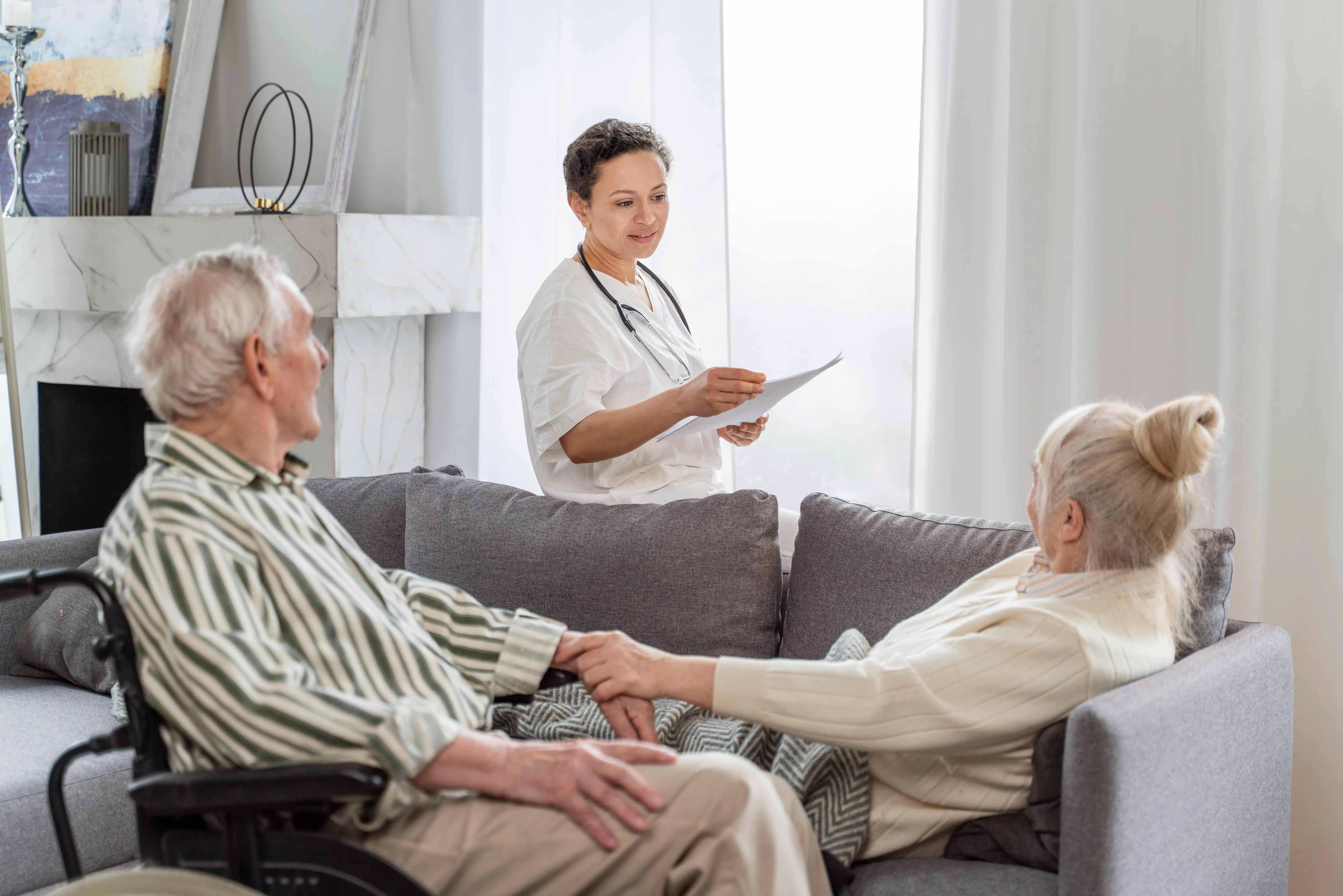 A woman in a wheelchair engages in conversation with an elderly couple, sharing smiles and friendly expressions.